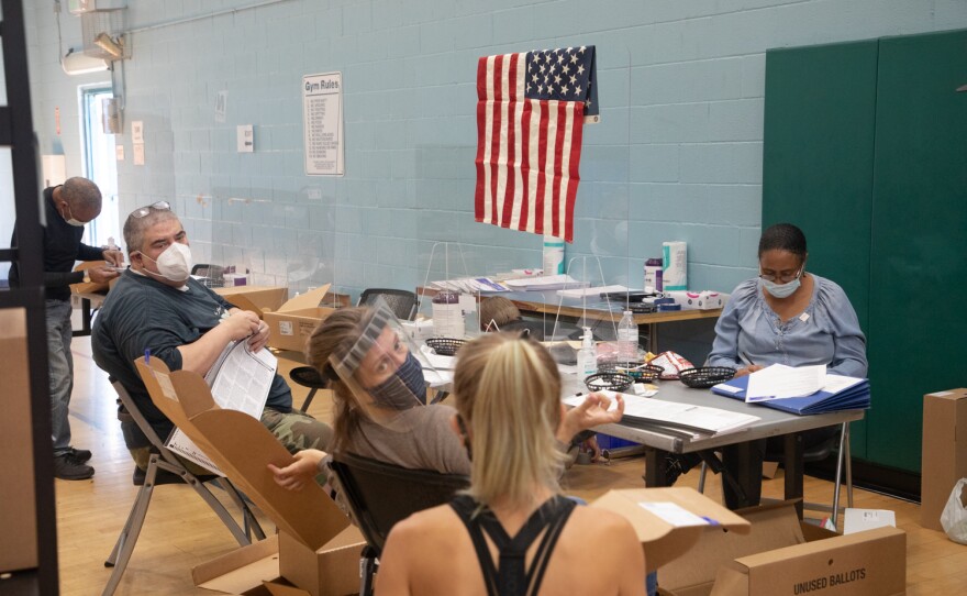 Poll workers count unused ballots in preparation for in-person voting at the Mid-City Gym in City Heights, Oct. 30, 2020