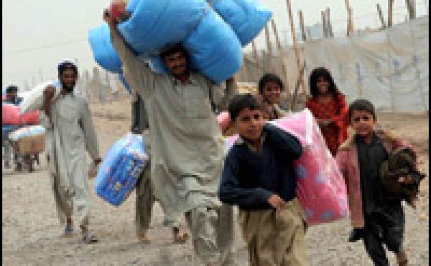 Pakistanis displaced from the Bajaur region by the military offensive carry relief goods at the Kacha Gari refugee camp near Peshawar on Dec. 7.