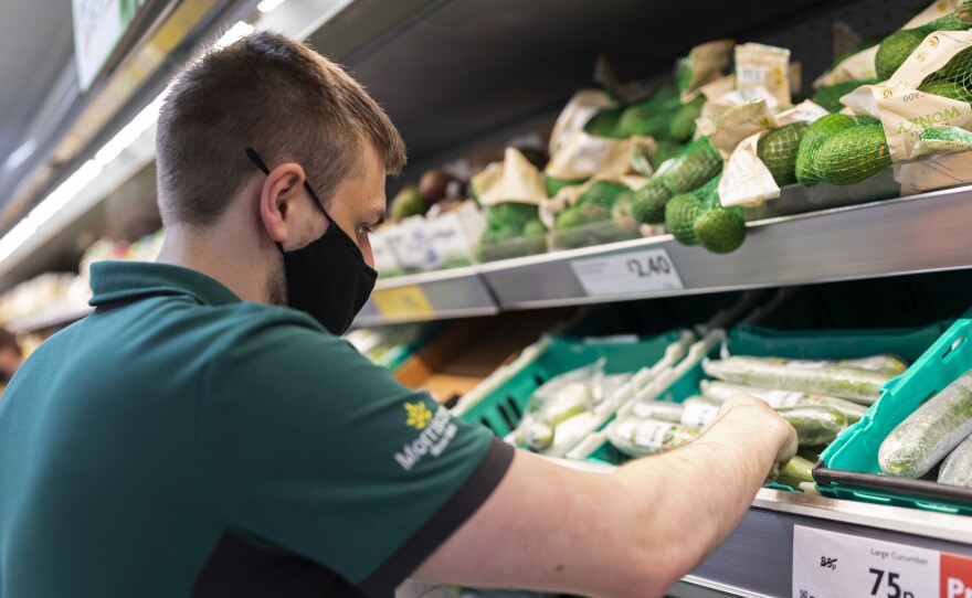 A uniformed member of staff wearing a face covering sorts through fresh produce in British supermarket chain Morrisons last month in Leeds, United Kingdom.