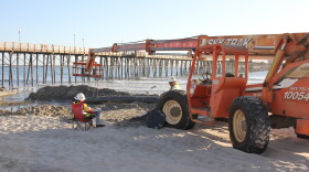 Sand dredged from the mouth of the Oceanside harbor is fed down the beach in a metal pipe and dropped next to the Oceanside pier, Oct. 15,  2016.  