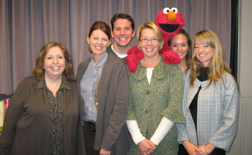 These Days team and Elmo. From left, Maureen Cavanaugh, Angela Carone, Hank Crook, Natalie Walsh, Elmo, Rachel Ferguson, and Megan Burke.