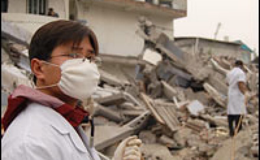 Health care workers spray disinfectant on the rubble of the school to prevent the spread of disease.
