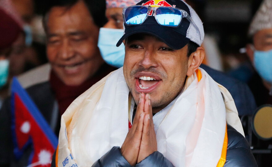 FILE - Nirmal Purja, one of the team members of the all-Nepalese mountaineering team that became the first to scale Mount K2 in winter, gestures as the team arrives at Tribhuwan International airport in Kathmandu, Nepal, Jan. 26, 2021.