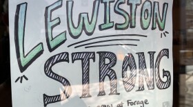 A "Lewiston Strong" sign hangs in the door of Forage Market in Lewiston, Maine.