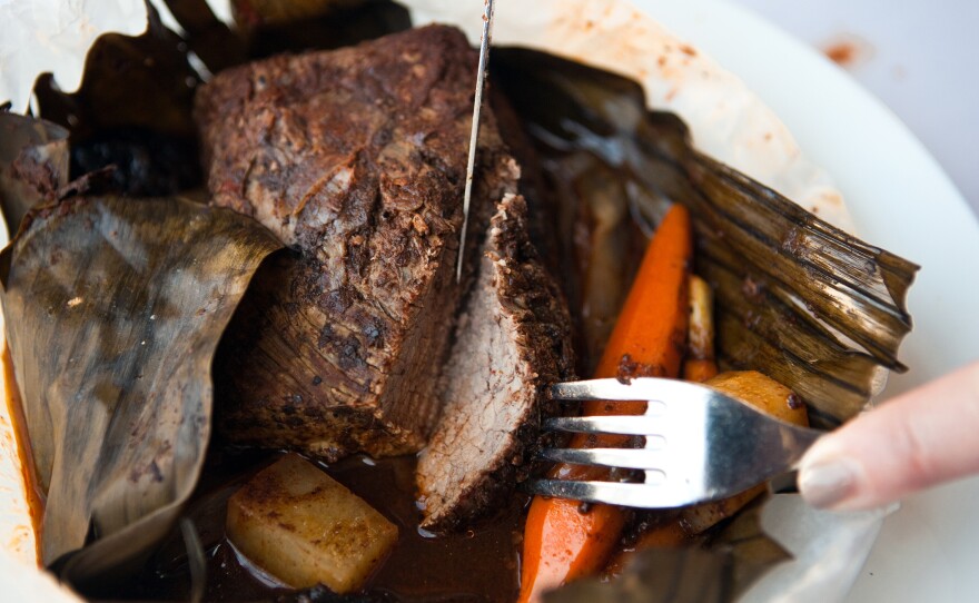Roasted brisket of barbecued beef wrapped in banana leaf with dried fruit tzimmes, served with glazed baby carrots.