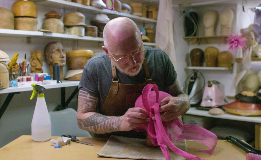 Ian Bennett adds his signature bow to his handmade hat.