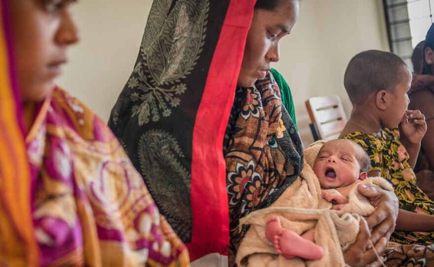 Rong Mala, 30, holds her 6-day-old child, Rakhal, as she waits to see the paramedic at a government clinic in Bangladesh.