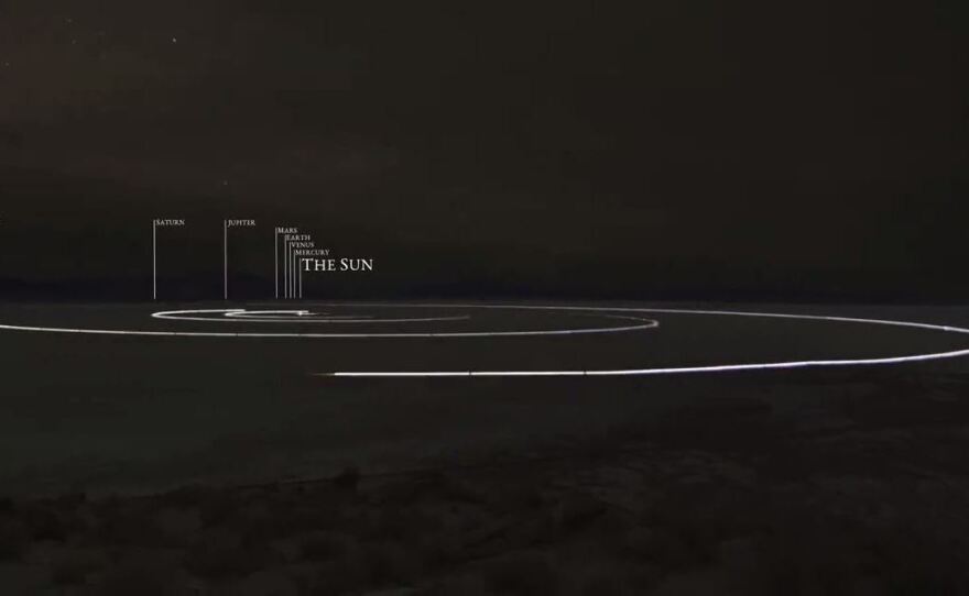 A still image from a video produced by the To Scale Series shows a model of the solar system in which planets orbit the sun on a dry lakebed in Nevada.