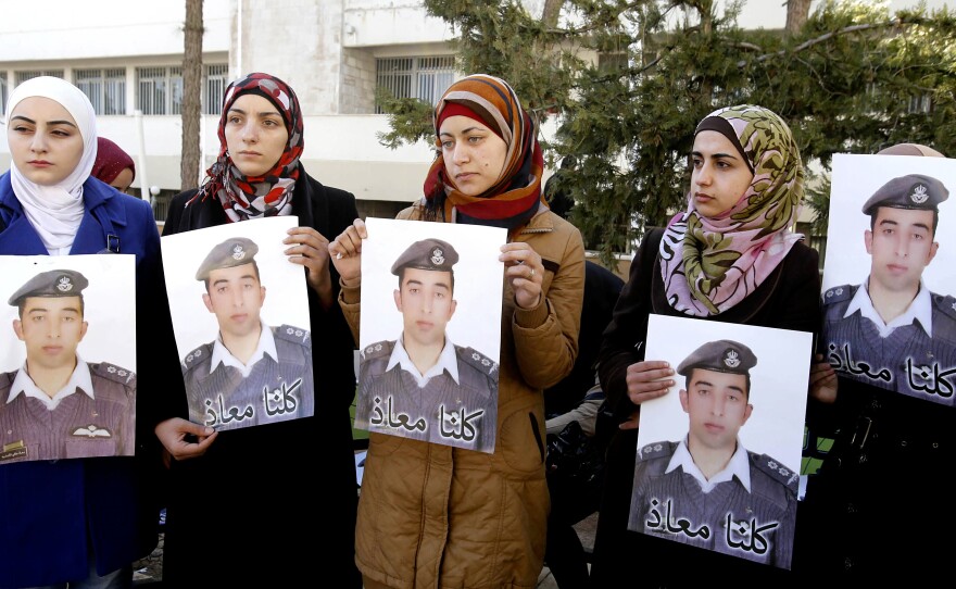 Anwar al-Tarawneh, center, the wife of Jordanian pilot Lt. Muath al-Kaseasbeh, holds a poster of him with Arabic that reads, "We are all Muath," during a rally in the capital Amman on Tuesday.