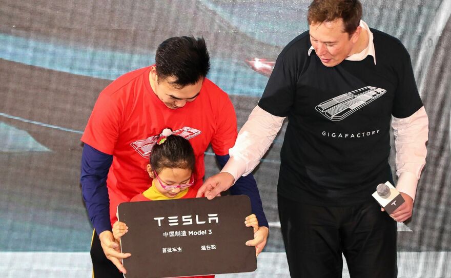 Tesla CEO Elon Musk gives a plaque to a child as buyers receive new cars during the Tesla China-made Model 3 Delivery Ceremony in Shanghai on Jan. 7, 2020. Companies like Tesla still see China as a key market as well as a production base.