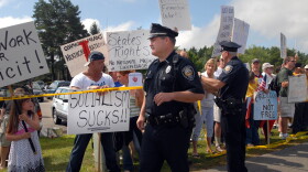 Police stand near protesters outside Portsmouth High School where U.S President Barack Obama is holding a town hall August 11, 2009 in Portsmouth, New Hampshire.