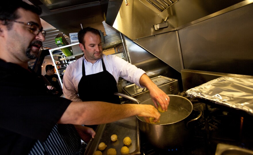 Barry Koslow shows Morning Edition host David Greene how to boil the rolled matzo balls. Koslow says he's rolled out hundreds of the starchy orbs each day during Passover.