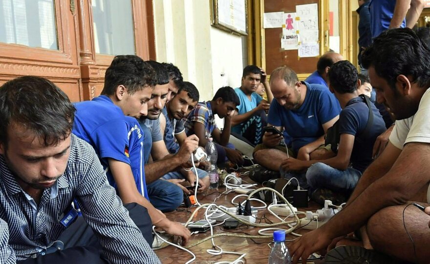 Migrants are charging their mobile phones at Keleti Railway Station in Budapest, Hungary, on Thursday.
