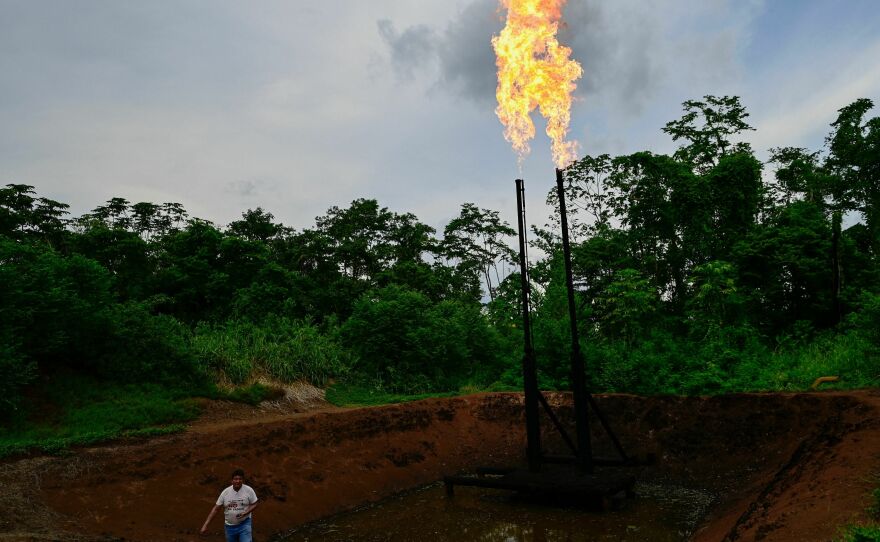 Flames flicker through the thick green trees of the Ecuadorian Amazon rainforest — where gas flares, oil wells and refineries darken the landscape and poison the environment — shown in Shushufindi, Ecuador, in 2023. The legacy there of Texaco, which Chevron acquired, has inspired lengthy legal battles in several countries.
