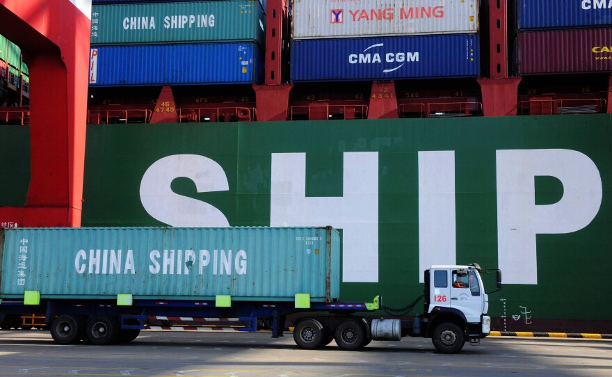 A truck carries a container past a ship at the port in Qingdao, in China's Shandong province on Feb. 15, 2016. China's sagging economy has hurt the shipping industry this year.