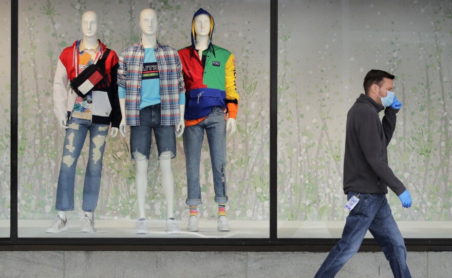 A man walks past mannequins in the windows of a Macy's store in Boston on April 15. The company said its online sales started growing in April, but they "only partially offset" the losses from its stores.