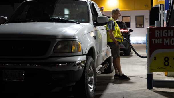 A person waits while filling their fuel tank at a gas station in Portland, Ore.