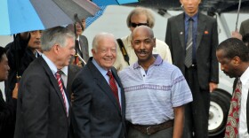 In this photo released by China's Xinhua news agency, former U.S. President Jimmy Carter, center left, poses with American Aijalon Gomes, center right, at Pyongyang airport, North Korea, on Friday Aug. 27, 2010.