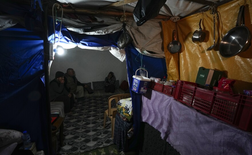 Earthquake survivor Rafet Donmez (center) sits on mattresses with his wife and son inside a tent in Antakya, southern Turkey, on Jan. 12.