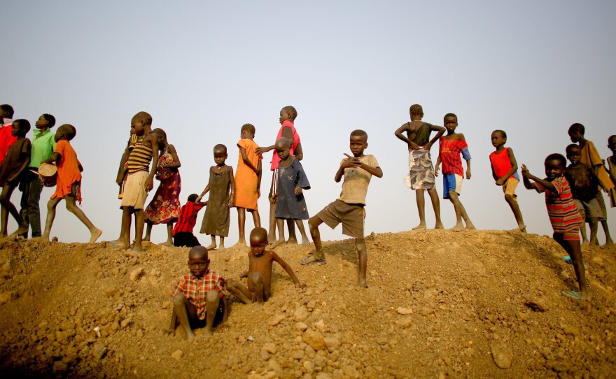 Children stand on top of an earthen dam in the camp in Bentiu. Massive dams, drainage canals and water retention pools were constructed after the camp flooded repeatedly during the rainy season. Residents say the water and mud was so deep in their huts that they had to sleep sitting up in chairs.