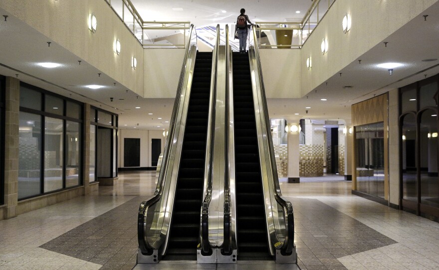 A woman rides an escalator past closed storefronts inside the largely empty White Flint Mall, in Bethesda, Md., in 2014. The mall closed last year.