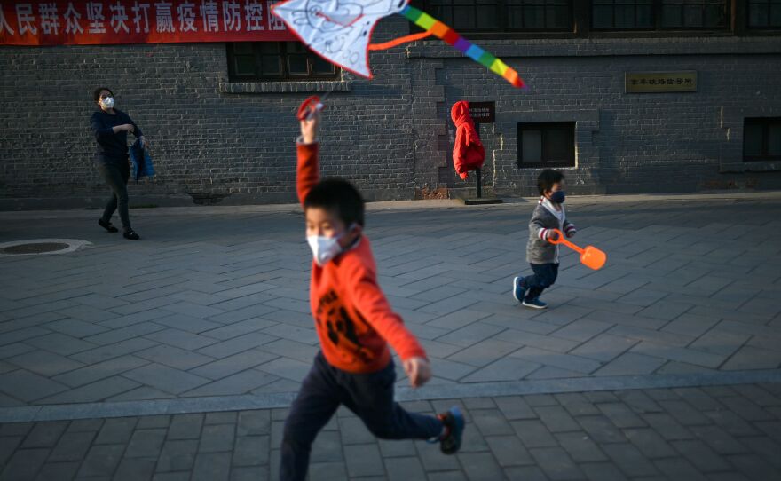 A boy wearing a face mask flies a kite at a park in Beijing. Researchers are studying the response of children to COVID-19.