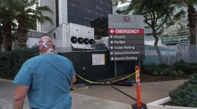A medical worker walks past a refrigerated trailer parked outside the Cedars-Sinai Medical Center in Los Angeles Thursday, Jan. 7, 2021.