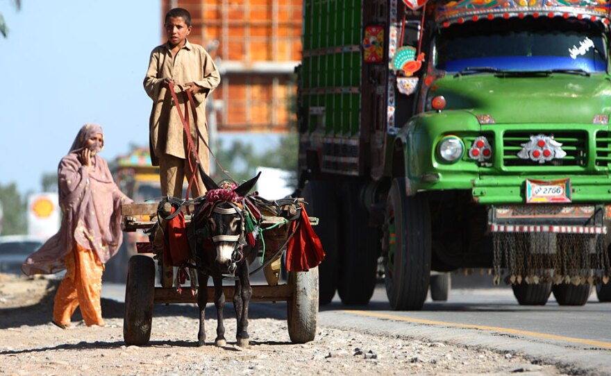 A boy drives a donkey cart along the shoulder of the Grand Trunk Road west of Islamabad, where old and new modes of transportation coexist.
