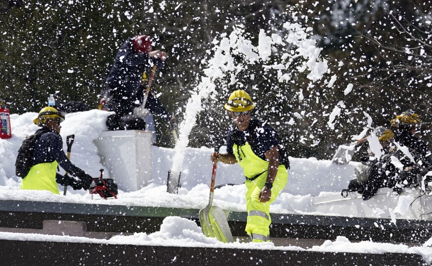 Members of a Cal Fire crew clear snow off the roof of the town's post office after a series of storms Wednesday, March 8, 2023, in Crestline, Calif. Residents of Southern California mountain towns are still struggling to dig out and get necessities in the aftermath of a record-setting blizzard last month that dumped so much snow that roads became impassable and roofs collapsed.