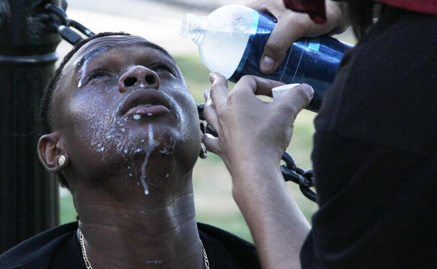 A protester helps rinse out the eyes of a fellow protester after being exposed to tear gas during a demonstration in downtown San Diego, May 31, 2020.