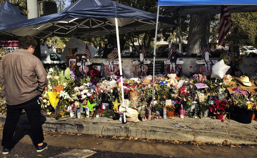 A passerby stops to look over a street side memorial to the shooting victims of the Borderline Bar in Thousand Oaks, Calif., on Tuesday. Investigators said the number of victims from the shooting at the country music bar could have been much higher based on the amount of ammunition the gunman carried.
