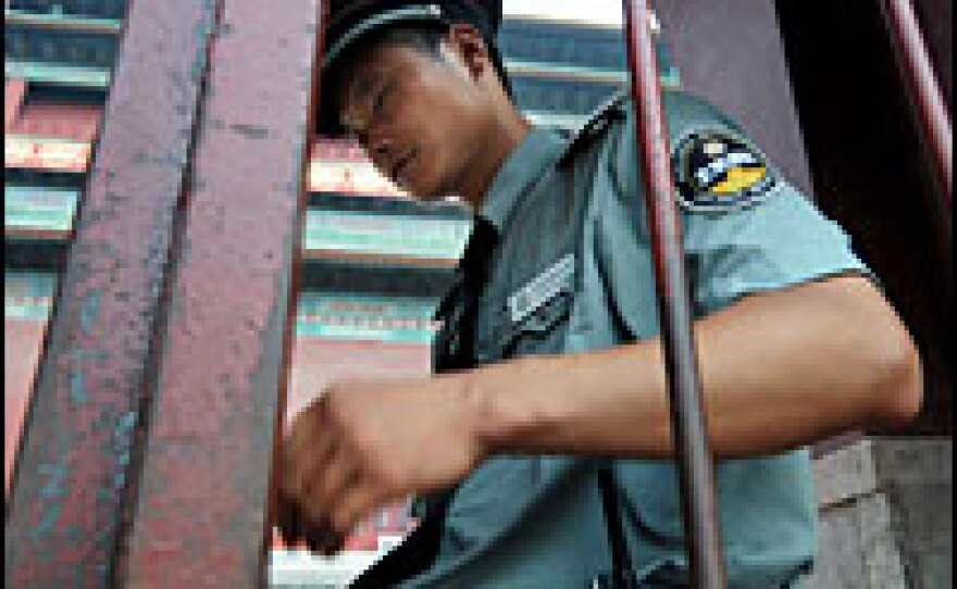 A Chinese security guard locks the gate at Beijing's historic Drum Tower, where a stabbing attack on Aug. 9, 2008, left one American dead and another injured. The victims were relatives of a U.S. Olympic coach.