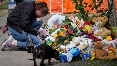 A woman cries as she lays down flowers in front of a house heavily damaged after a Russian strike on residential neighbourhood in Kyiv, Ukraine, on Friday, May 15, 2026.