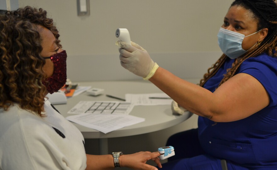 Rotonia Gates, a nurse, checks the temperature of Tonya Beamon of Renova, Miss. on March 3. Beamon decided to get her COVID-19 vaccine at the Delta Health Center because she had heard good things about the staff.