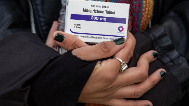 An abortion-rights activist holds a box of mifepristone pills as demonstrators from both anti-abortion and abortion-rights groups rally outside the Supreme Court in Washington on March 26, 2024.