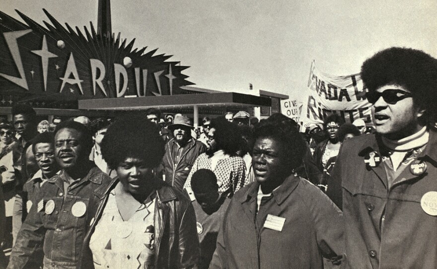 Ralph Abernathy, Ruby Duncan, and George Wiley hand in hand in the Operation Nevada crowd, the Stardust Hotel behind them.