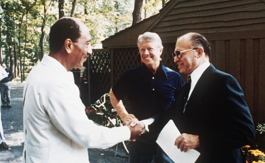Egyptian President Anwar Sadat, left, shakes hands with Israeli Premier Menachem Begin, as U.S. President Jimmy Carter looks on, Sept. 6, 1977, at Camp David.