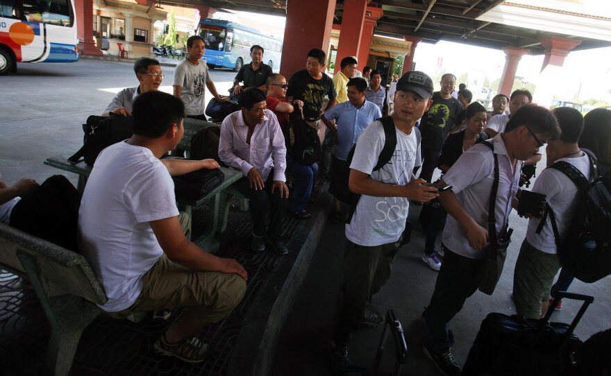 Chinese nationals stand by their belongings after crossing to Cambodia from Vietnam at the Bavet international checkpoint in Svay Rieng province, on Thursday. May 15, 2014. Hundreds of Chinese are fleeing the country as unrest escalates.