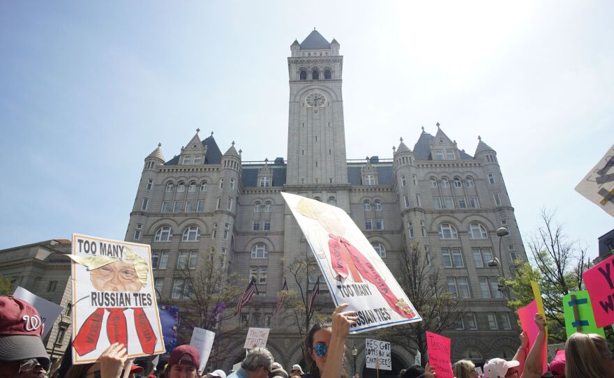 Protestors demonstrating April 15 against President Trump's purported ties to foreign governments walk by the Trump hotel during in Washington, D.C.