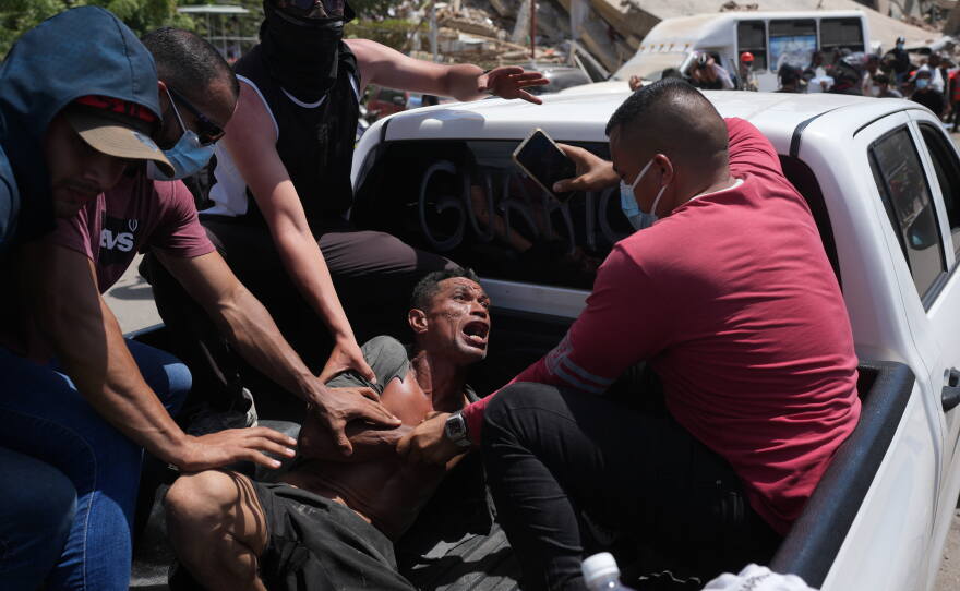 Residents transport a man rescued from the rubble three days after earthquakes struck, in La Guaira, Venezuela, Saturday, June 27, 2026.