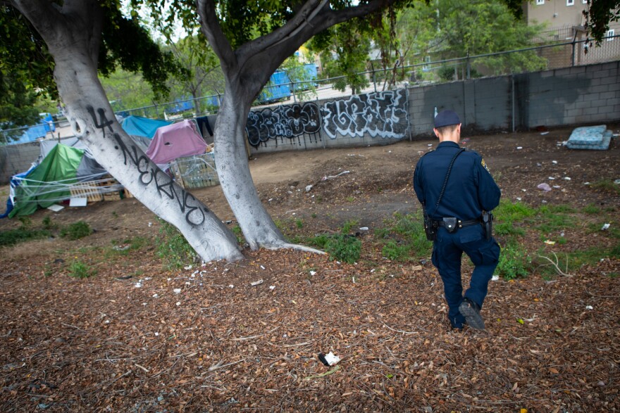 California Highway Patrol Officer Jesse Matias approaches an encampment along the side of the freeway in San Ysidro, April 28, 2022