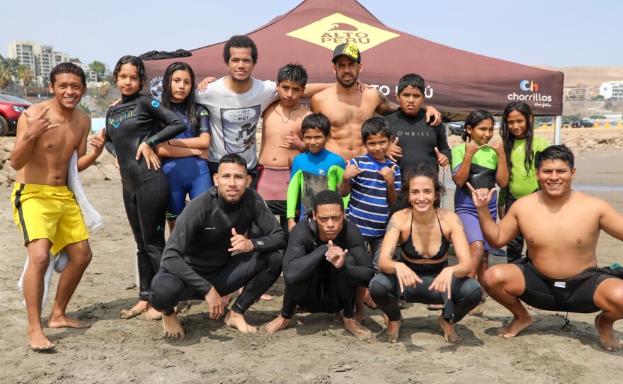 Surf instructors and kids on Playa Sombrillas beach in Lima.