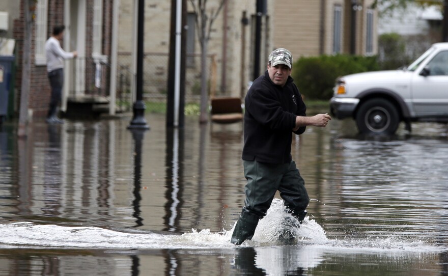 A man crosses a flooded street in the wake of Superstorm Sandy on Thursday in Little Ferry, N.J. Surprise coastal surge floods caused by the storm battered Little Ferry, Moonachie and some other towns along the Hackensack River in Bergen County, all areas unaccustomed to flooding.