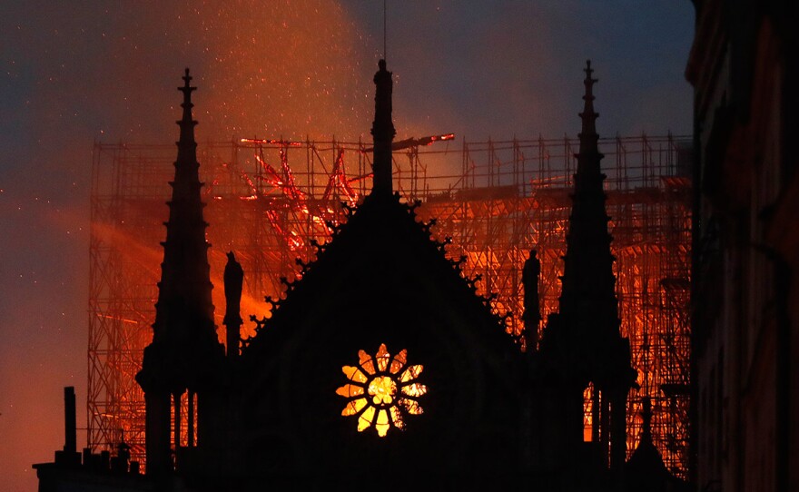 Flames and smoke rise from Notre Dame cathedral as it burns in Paris, Monday, April 15, 2019. Massive plumes of yellow-brown smoke are filling the air above Notre Dame Cathedral and ash is falling on tourists and others around the island that marks the center of Paris.