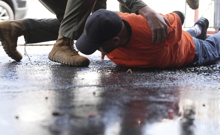A man is detained by immigration agents at a car wash on Friday, Aug. 15, 2025, in Montebello, Calif.