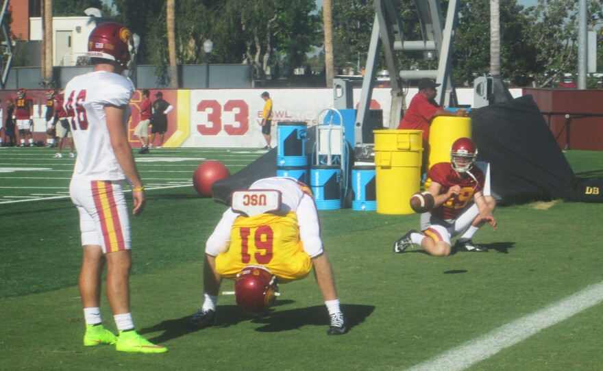Jake Olson, in the yellow jersey, snaps the football on the USC practice field. The 18-year-old lost his sight at age 12, and now is a walk-on reserve long snapper for the USC Trojans.