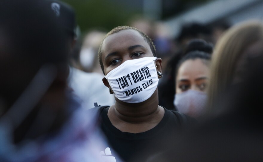 A man at a vigil this week wears a mask with the words "I can't breathe" above the name of Manuel Ellis, a 33-year-old black man whose death in Tacoma, Wash., police custody was recently ruled a homicide.