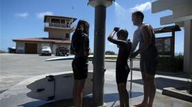 Steven Gibbs, right, his son Samuel, 10, and daughter Sophia, 12, use an outdoor rinse station at Doheny State Beach in Dana Point, Calif., Thursday, July 9, 2015.