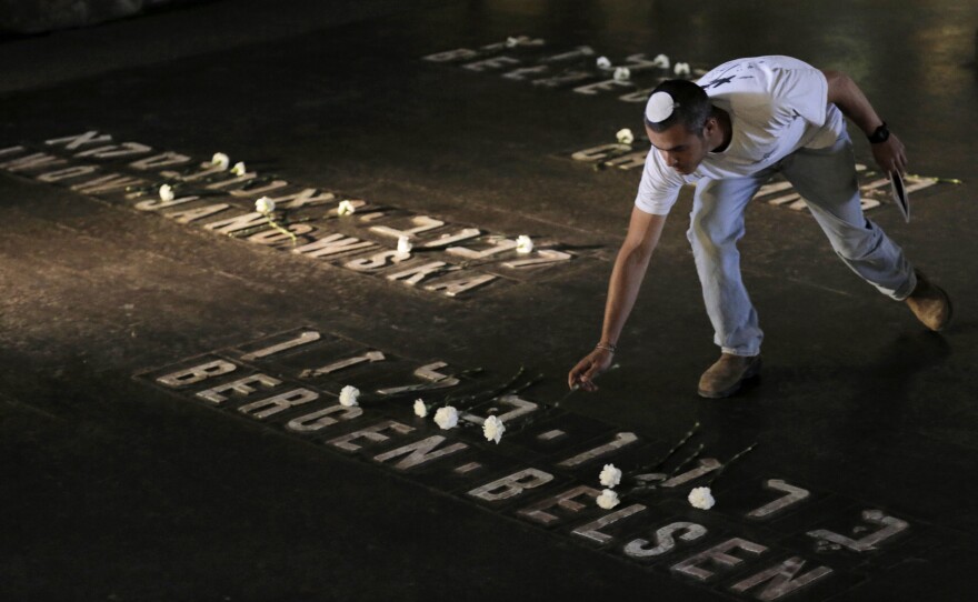 An Israeli places a flower beside the name of the World War II Nazi concentration camp Bergen Belsen during a ceremony marking Holocaust Remembrance Day at Yad Vashem in Jerusalem, on April 28. The Israeli government is weighing a new plan that would get more financial help to elderly Holocaust survivors, including about 50,000 in the country who are living below the poverty line.