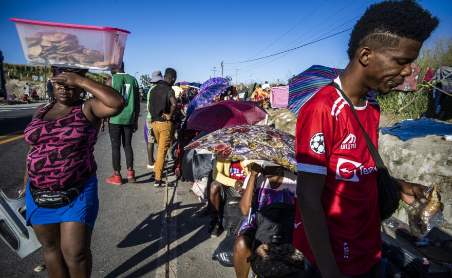 Haitian migrant Djeeff Orelien lines up on the side of a highway for buses provided by the INM, the National Migration Institute, Mexico's immigration agency.